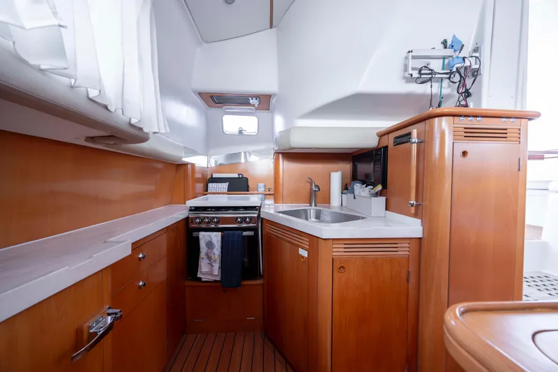  Yacht Photos Pics Interior of 2004 Lagoon 43 PC yacht kitchen with wooden cabinetry and modern appliances.