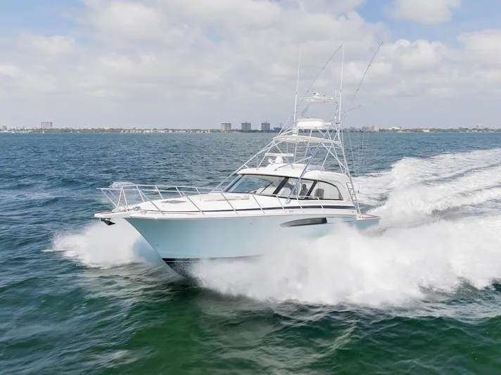  Yacht Photos Pics 2022 Bertram 50 yacht cruising swiftly on open water under a partly cloudy sky.