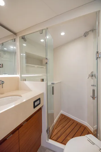  Yacht Photos Pics Modern bathroom in 2022 Bertram 50 yacht with glass shower and wooden accents.
