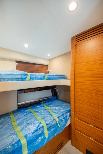  Yacht Photos Pics 2022 Bertram 50 yacht interior with wooden bunk beds and blue mattresses.