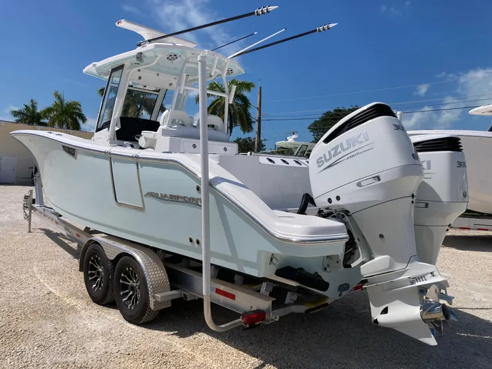  Yacht Photos Pics 2025 Aquasport 28AS boat on trailer with Suzuki outboard motor, parked outdoors.