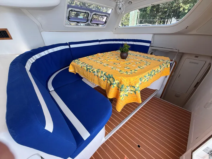 Tiki Yacht Photos Pics Interior of 2003 Leopard 38 yacht with blue seating and yellow tablecloth.