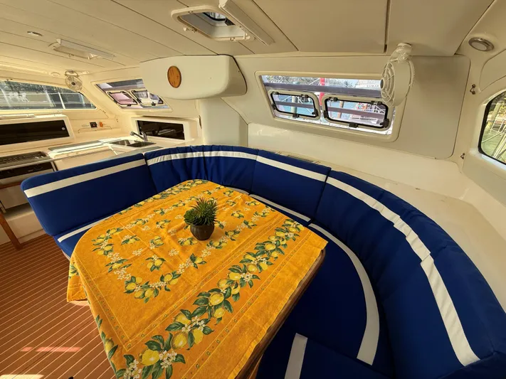 Tiki Yacht Photos Pics Cozy interior of 2003 Leopard 38 yacht with blue seating and vibrant yellow tablecloth.