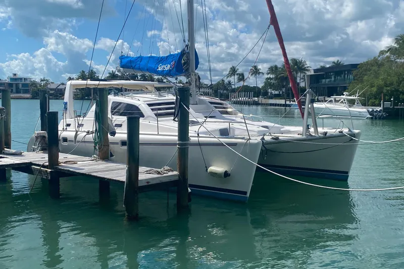 Tiki Yacht Photos Pics 2003 Leopard 38 catamaran docked in a sunny marina with palm trees.