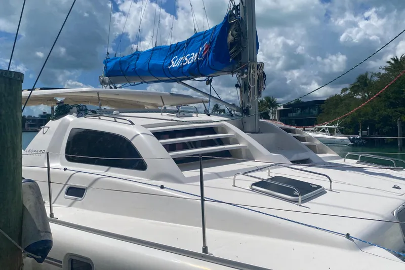 Tiki Yacht Photos Pics 2003 Leopard 38 catamaran docked, featuring a blue sail cover under a partly cloudy sky.