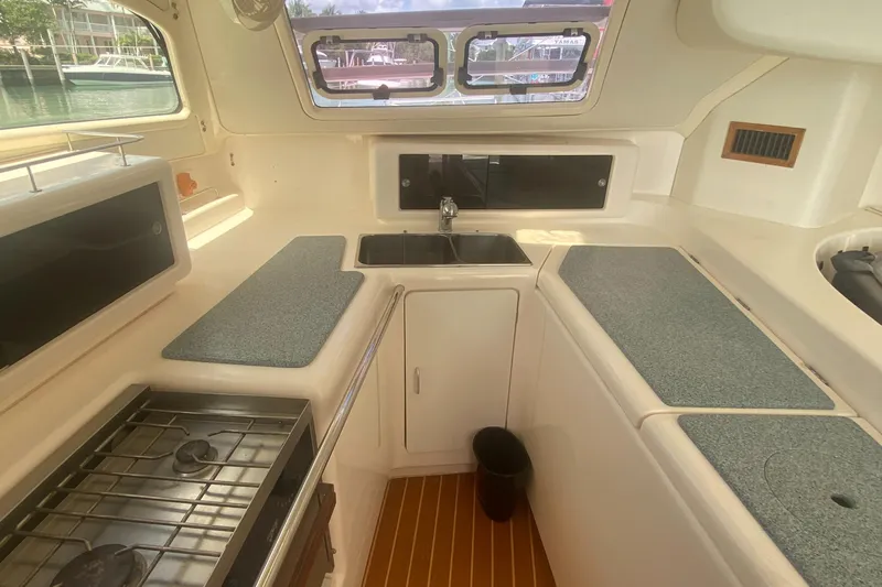 Tiki Yacht Photos Pics Compact kitchen in a 2003 Leopard 38 catamaran with stove, sink, and ample counter space.