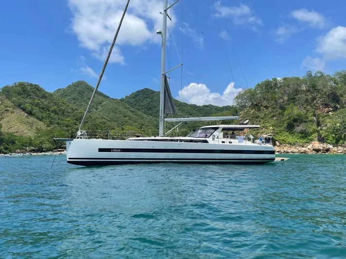 Gwint Yacht Photos Pics 2019 Beneteau Oceanis Yacht 62 sailing in a scenic bay with lush green hills.