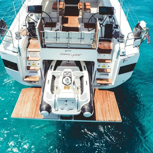 Gwint Yacht Photos Pics 2019 Beneteau Oceanis Yacht 62 with tender, docked on turquoise water.