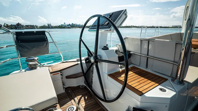 Gwint Yacht Photos Pics Steering wheel of 2019 Beneteau Oceanis Yacht 62, overlooking serene blue waters.
