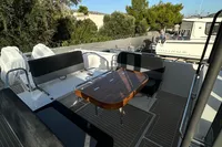 2024 Nimbus T11 X-Edition boat deck with seating and table, surrounded by trees.