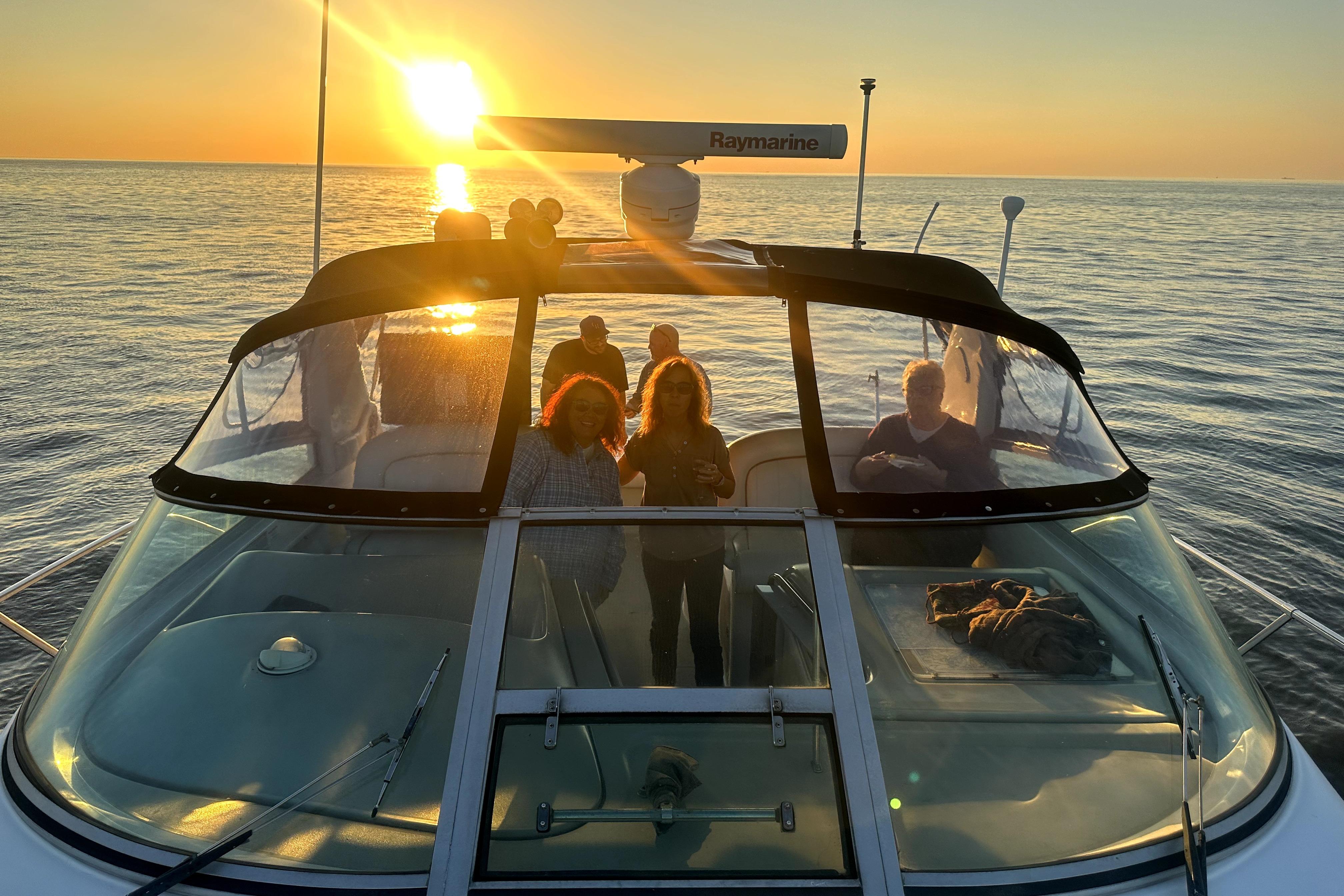 1998 Sea Ray 340 Amberjack at sunset with people on deck, ocean view.
