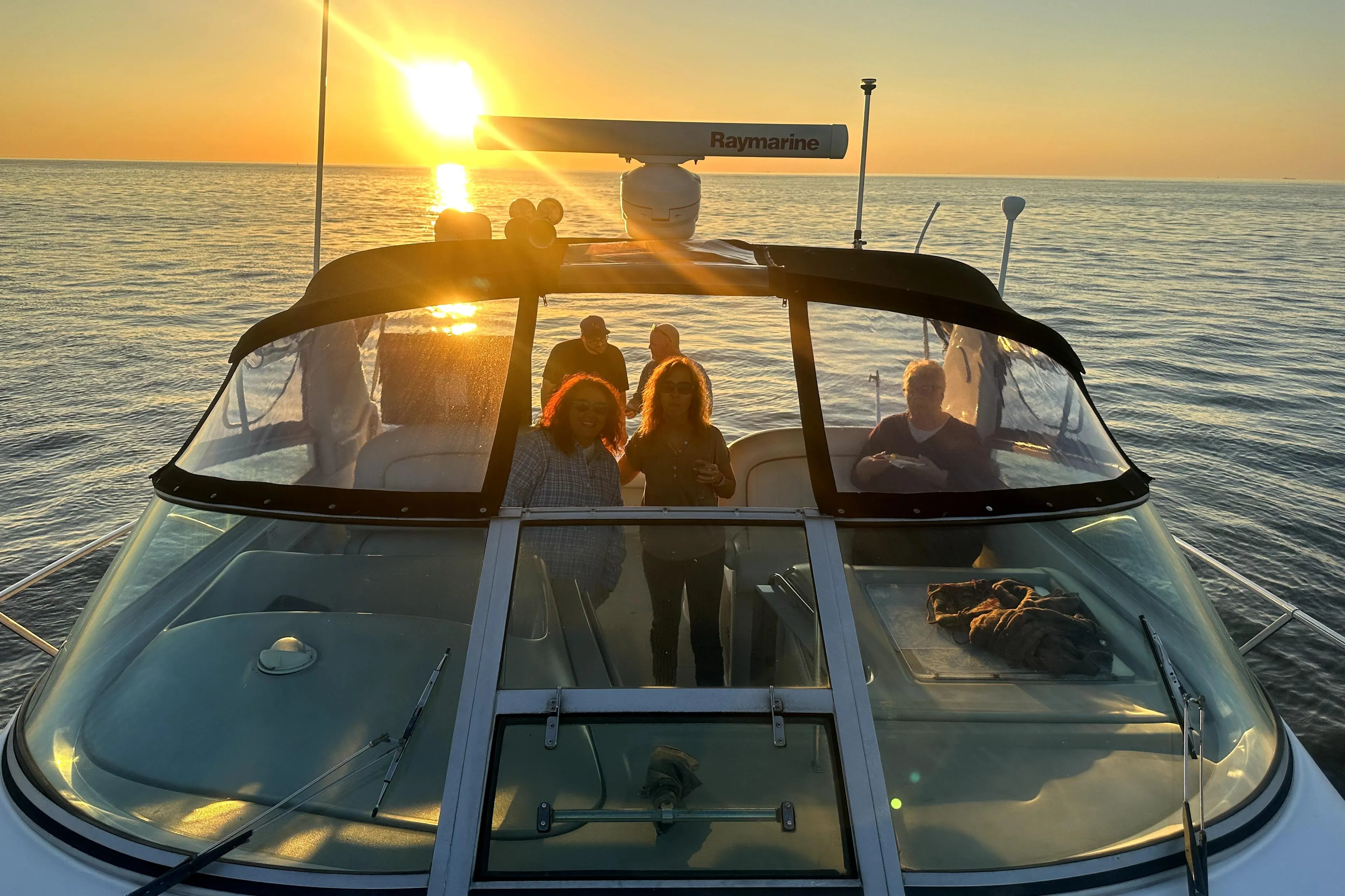 1998 Sea Ray 340 Amberjack at sunset with people on deck, ocean view.