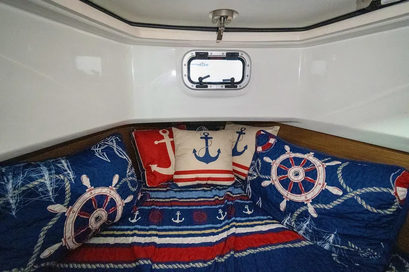  Yacht Photos Pics Cozy cabin interior of 2020 Jeanneau Leader 9.0 CC with nautical-themed bedding.