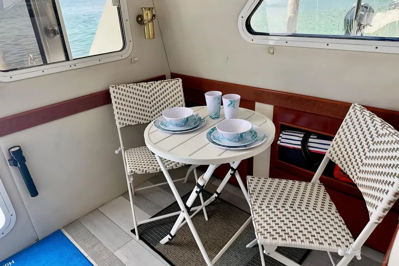  Yacht Photos Pics Cozy dining setup on 2001 Zeta 32 Power Cat with wicker chairs and nautical tableware.