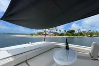 Aquila Molokai 28 yacht with shaded deck, champagne, and tropical island view, 2022 model.