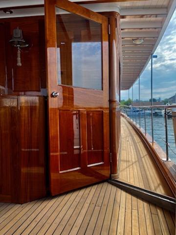 1947 Trumpy Raised Pilot House yacht with wooden deck and open door.