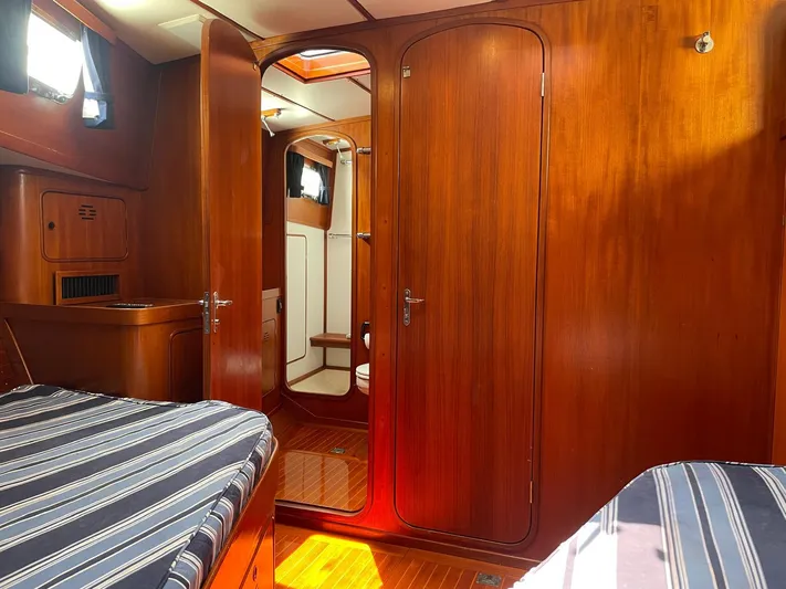 Southerly Yacht Photos Pics Interior of 1990 Lyman-Morse 52 yacht with wooden paneling and striped bedding.