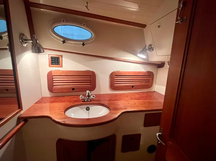  Yacht Photos Pics 2005 Hinckley Picnic Boat EP bathroom with wooden cabinetry and oval porthole window.