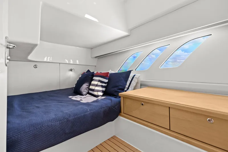 Damn Lucky Yacht Photos Pics Cabin interior of 2019 Intrepid 475 boat with bed and wooden drawers.