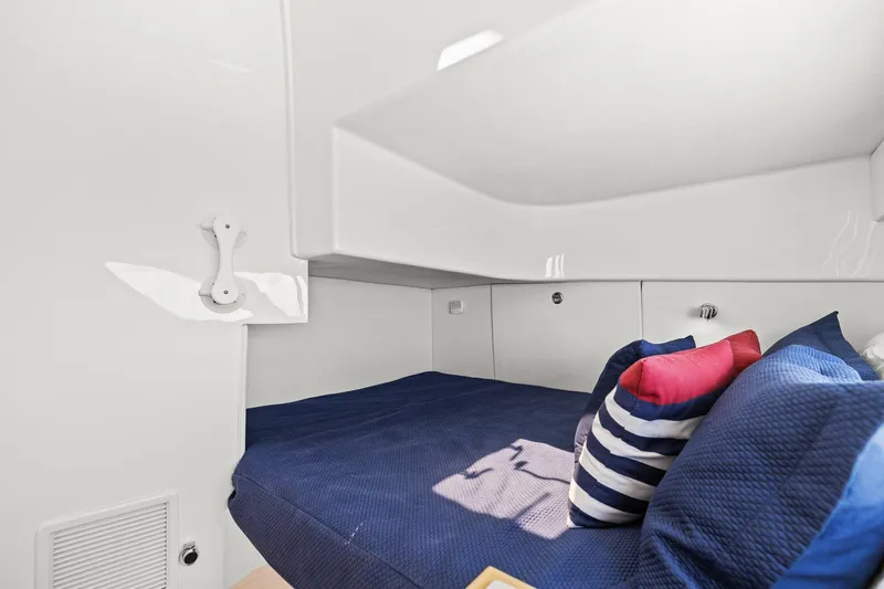 Damn Lucky Yacht Photos Pics Cozy cabin interior of 2019 Intrepid 475 with blue bedding and striped pillows.