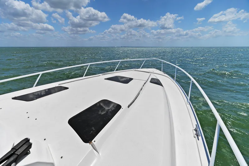 Damn Lucky Yacht Photos Pics Bow view of 2019 Intrepid 475 boat cruising on open sea under blue sky.