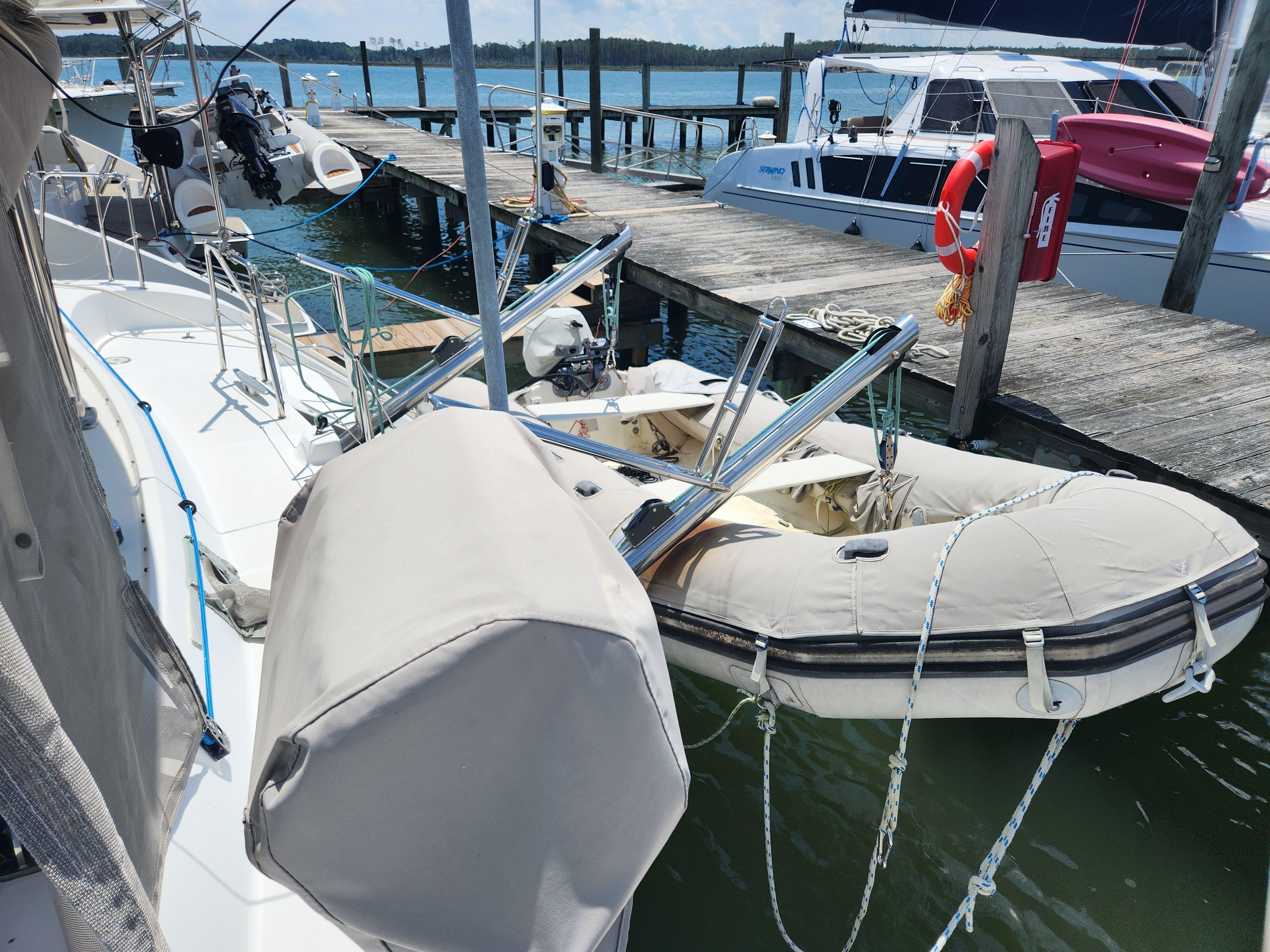 2006 Lagoon 440 catamaran docked with inflatable dinghy, marina background.