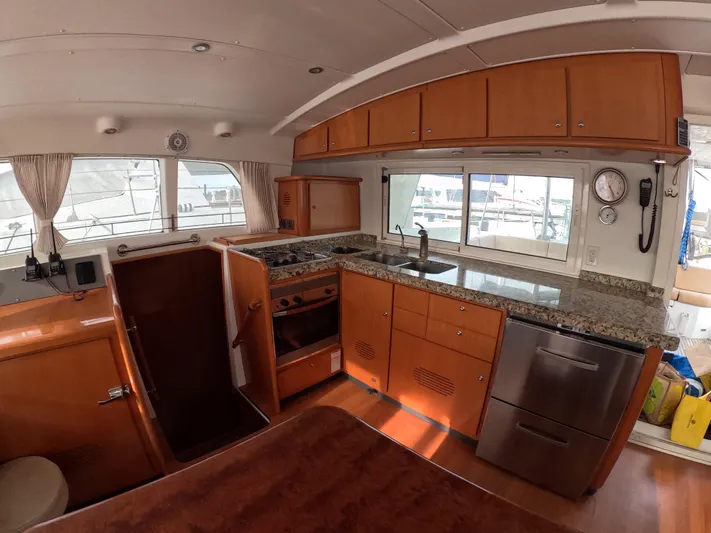 Orion Yacht Photos Pics Interior of a 2006 Lagoon 440 yacht featuring a modern kitchen with wood cabinetry.