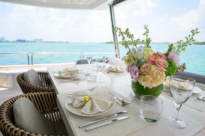  Yacht Photos Pics Elegant dining setup on 2024 Sirena 88 yacht with ocean view and floral centerpiece.
