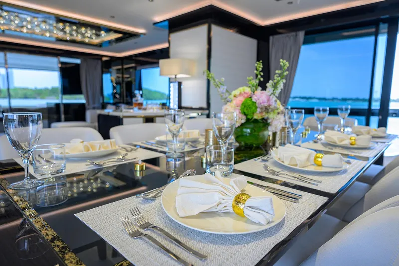  Yacht Photos Pics Luxurious dining setup on 2024 Sirena 88 yacht, featuring elegant tableware and floral centerpiece.