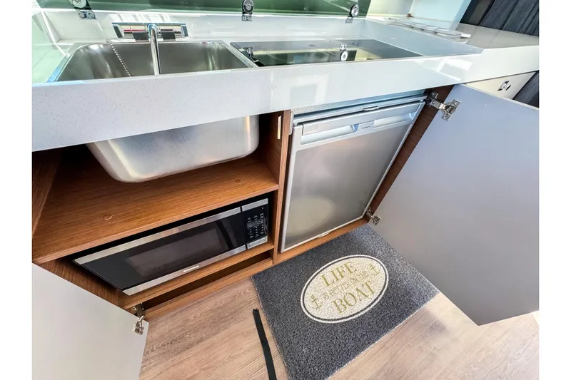  Yacht Photos Pics Modern kitchen area in 2023 Beneteau Antares 11 with sink, microwave, and fridge.