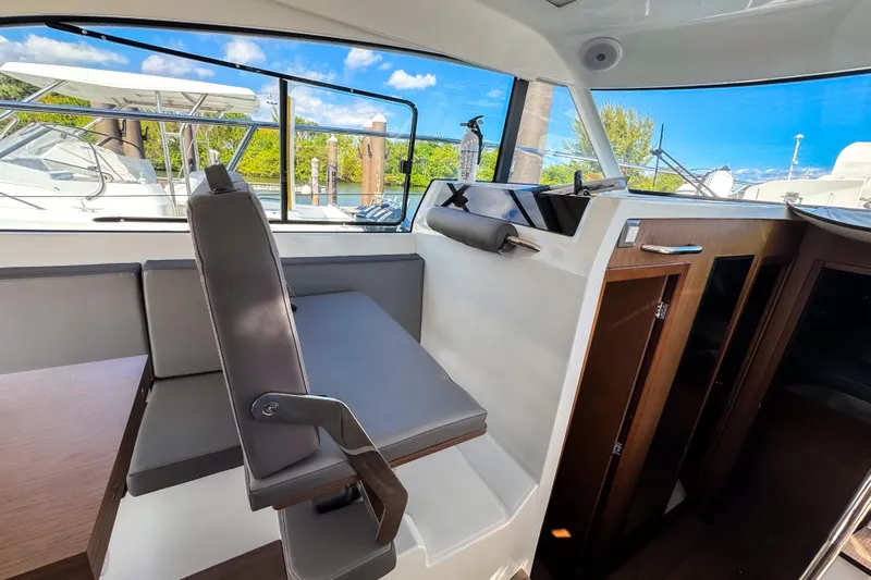  Yacht Photos Pics Interior of 2023 Beneteau Antares 11, featuring seating and wooden cabinetry with scenic window views.