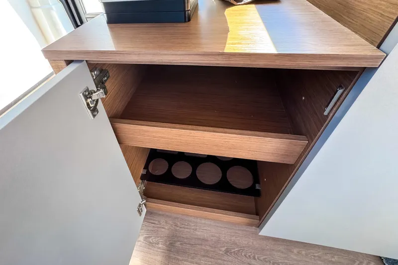  Yacht Photos Pics Open wooden cabinet inside 2023 Beneteau Antares 11 boat, featuring shelves and storage space.
