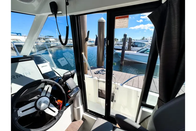  Yacht Photos Pics Interior view of 2023 Beneteau Antares 11 boat, showcasing helm and marina.