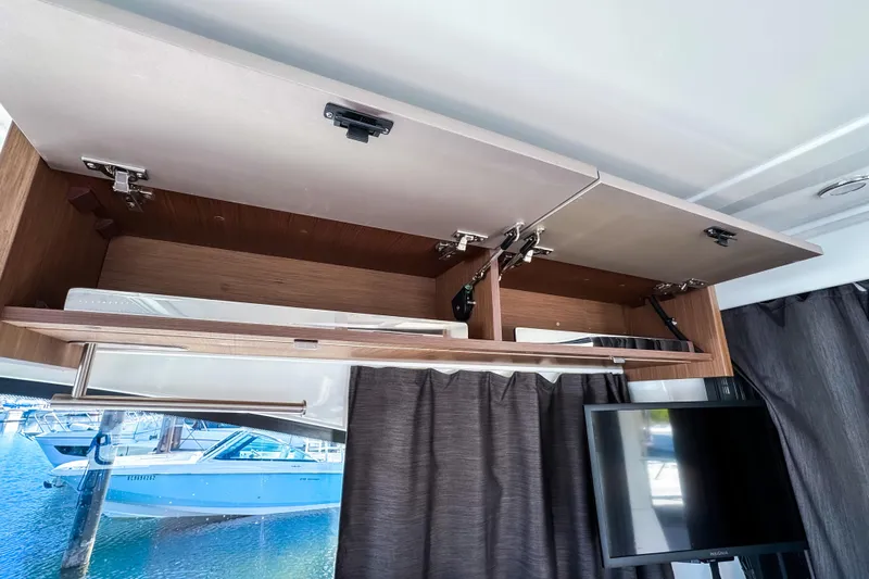  Yacht Photos Pics Interior of 2023 Beneteau Antares 11 with open wooden cabinets and a view of the marina.