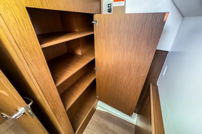  Yacht Photos Pics Open wooden cabinet with shelves inside a 2023 Beneteau Antares 11 boat.