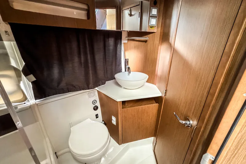  Yacht Photos Pics 2023 Beneteau Antares 11 bathroom with modern sink and wooden cabinetry.