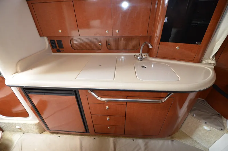 Serenity Yacht Photos Pics 2004 Sea Ray 340 Sundancer galley with wood cabinets, sink, and mini fridge.