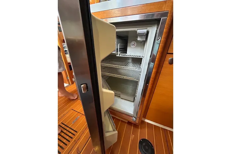Deiopea Yacht Photos Pics Open refrigerator on 2013 Italia Yachts IY13.98, showcasing interior shelves and wooden flooring.