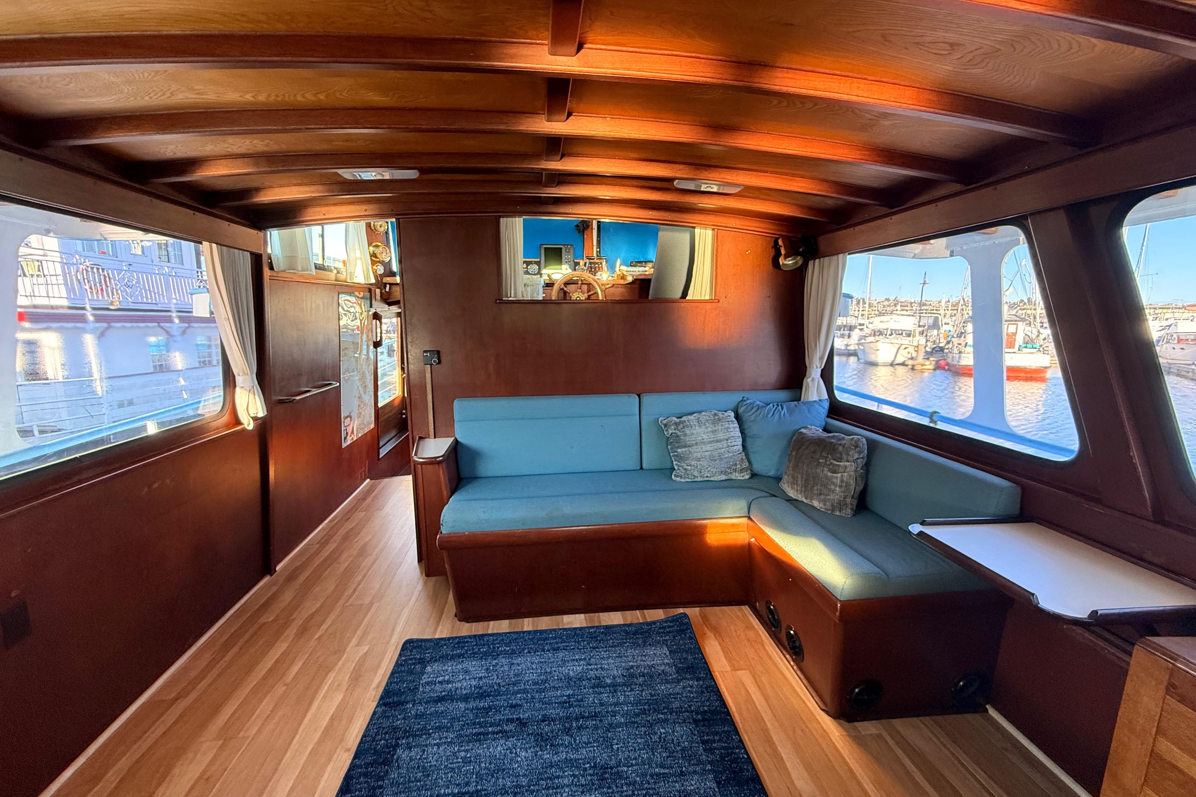 Interior of a 1965 custom trawler with wooden paneling and blue seating.