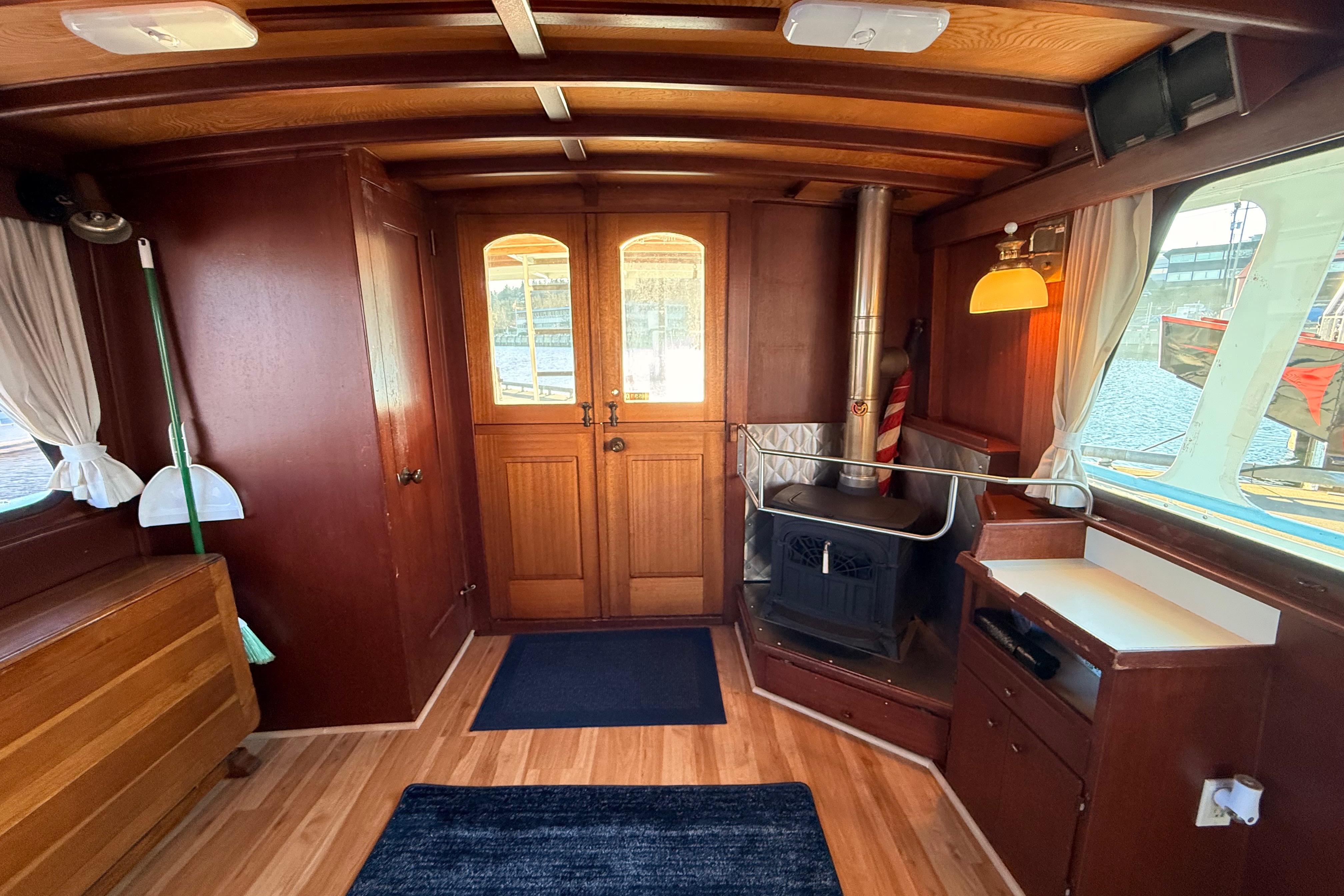 Interior of a 1965 Custom Trawler with wood paneling and a cozy stove.