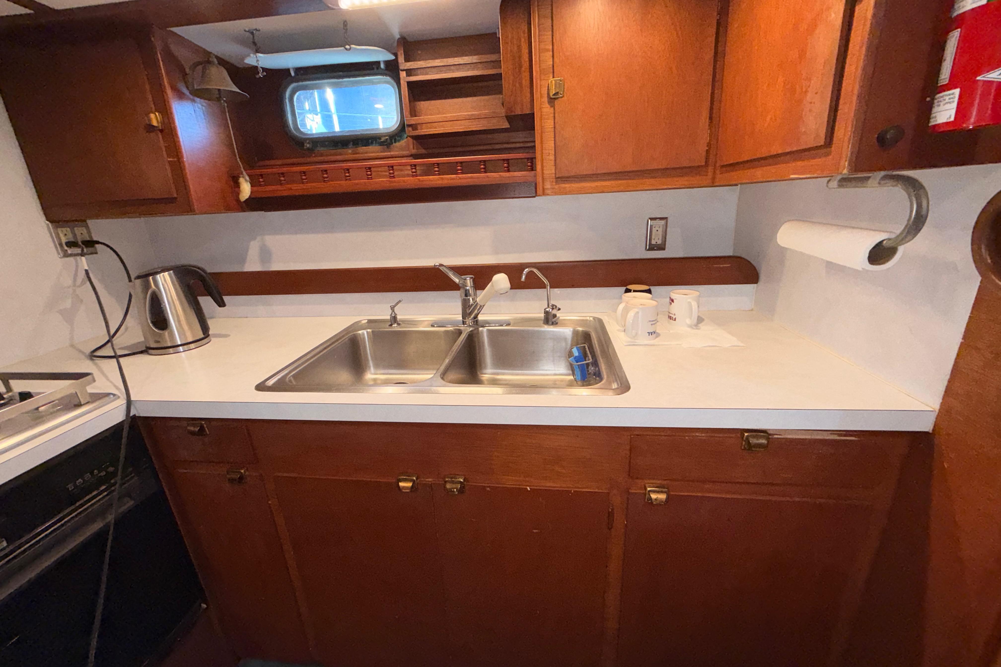 Vintage 1965 Custom Trawler kitchen with wooden cabinets and dual sink.