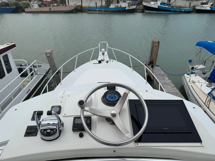 Pandemonium Yacht Photos Pics Helm of 2000 Liberty 42 Express yacht docked at marina, featuring steering wheel and controls.