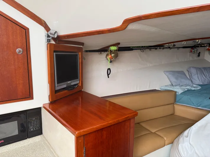 Pandemonium Yacht Photos Pics Interior of 2000 Liberty 42 Express yacht with TV, seating, and fishing rods.