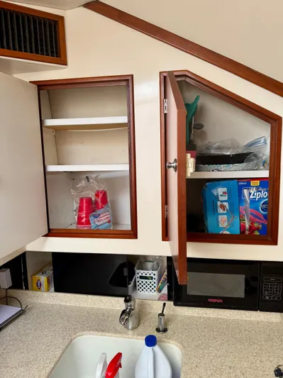 Pandemonium Yacht Photos Pics Kitchen area in a 2000 Liberty 42 Express boat with open cabinets and countertop items.