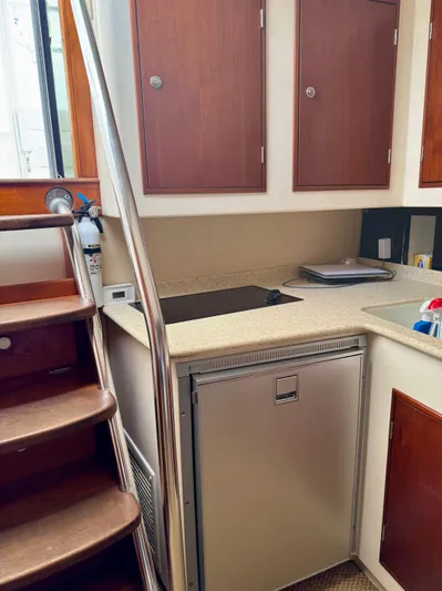 Pandemonium Yacht Photos Pics Compact kitchen area in a 2000 Liberty 42 Express boat with wooden cabinets and stainless steel appliances.