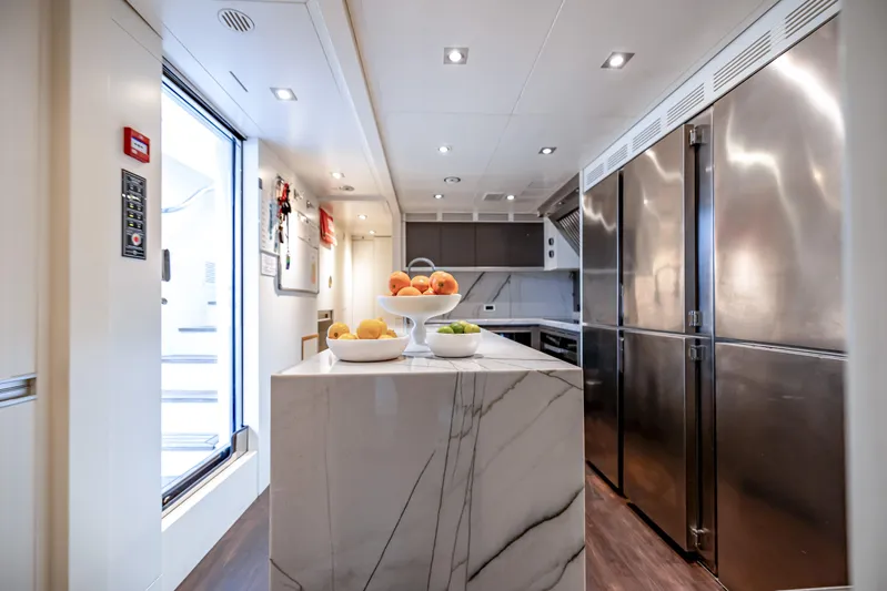 Patience Yacht Photos Pics Luxurious kitchen interior on 2012 Benetti Classic Supreme 132 yacht, featuring marble island and stainless steel appliances.