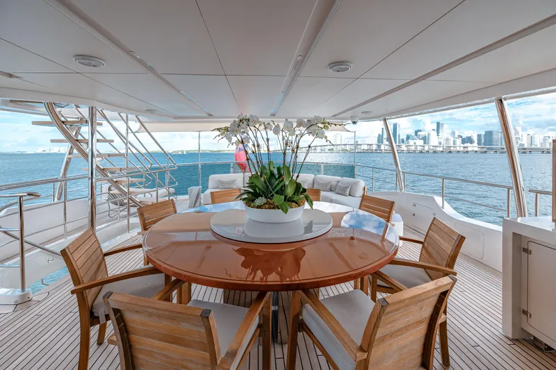Patience Yacht Photos Pics Luxurious Benetti Classic Supreme 132 yacht deck with elegant dining area, overlooking serene ocean view.