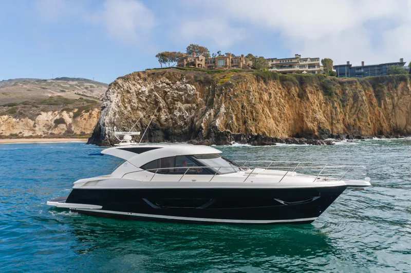 No Contingencies Yacht Photos Pics 2012 Riviera 44 Sport Yacht cruising near scenic coastal cliffs.