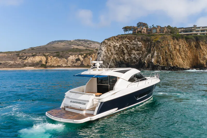 No Contingencies Yacht Photos Pics 2012 Riviera 44 Sport Yacht cruising near scenic coastal cliffs.