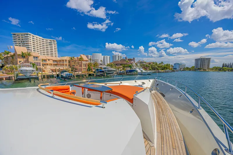  Yacht Photos Pics Luxurious 2010 Lazzara LSX 92 yacht with vibrant orange seating, docked near waterfront buildings.